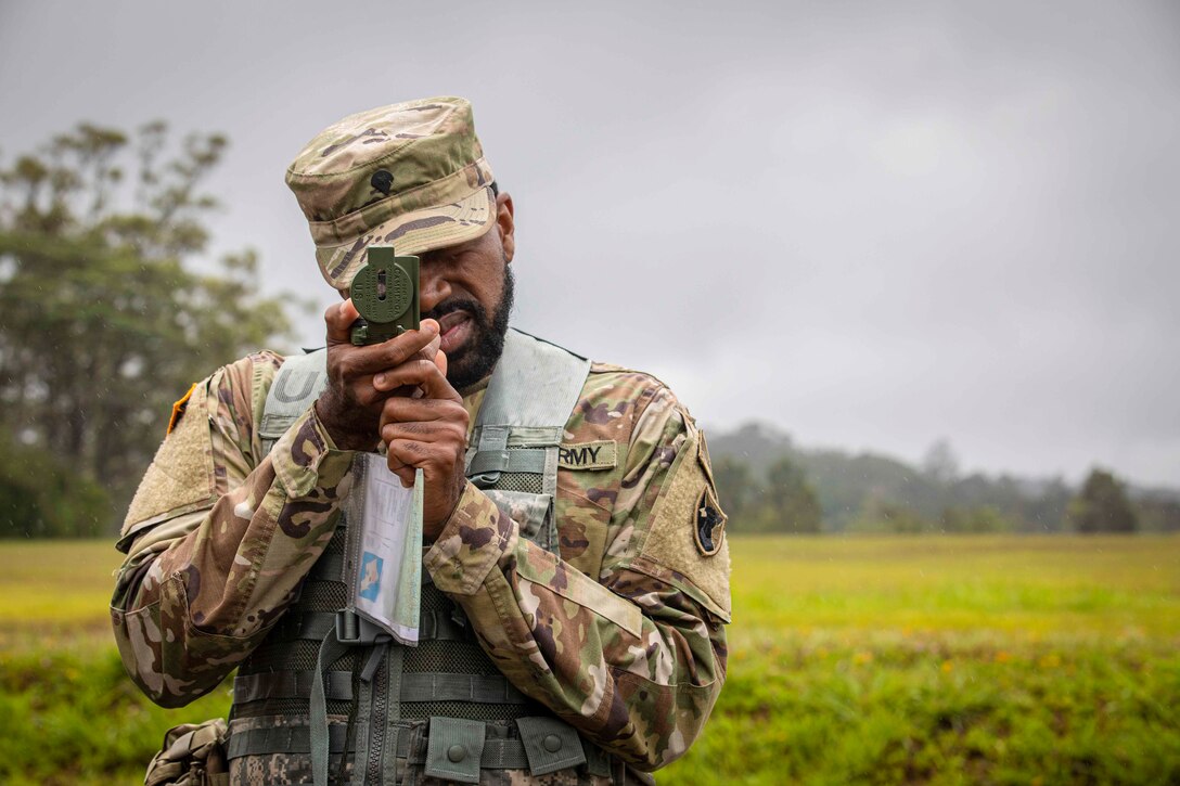 A soldier looks through a compass.