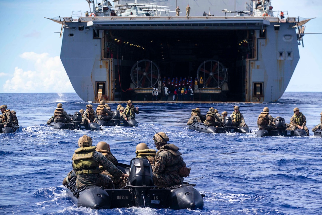 Marines move toward a ship in combat rubber raiding crafts.