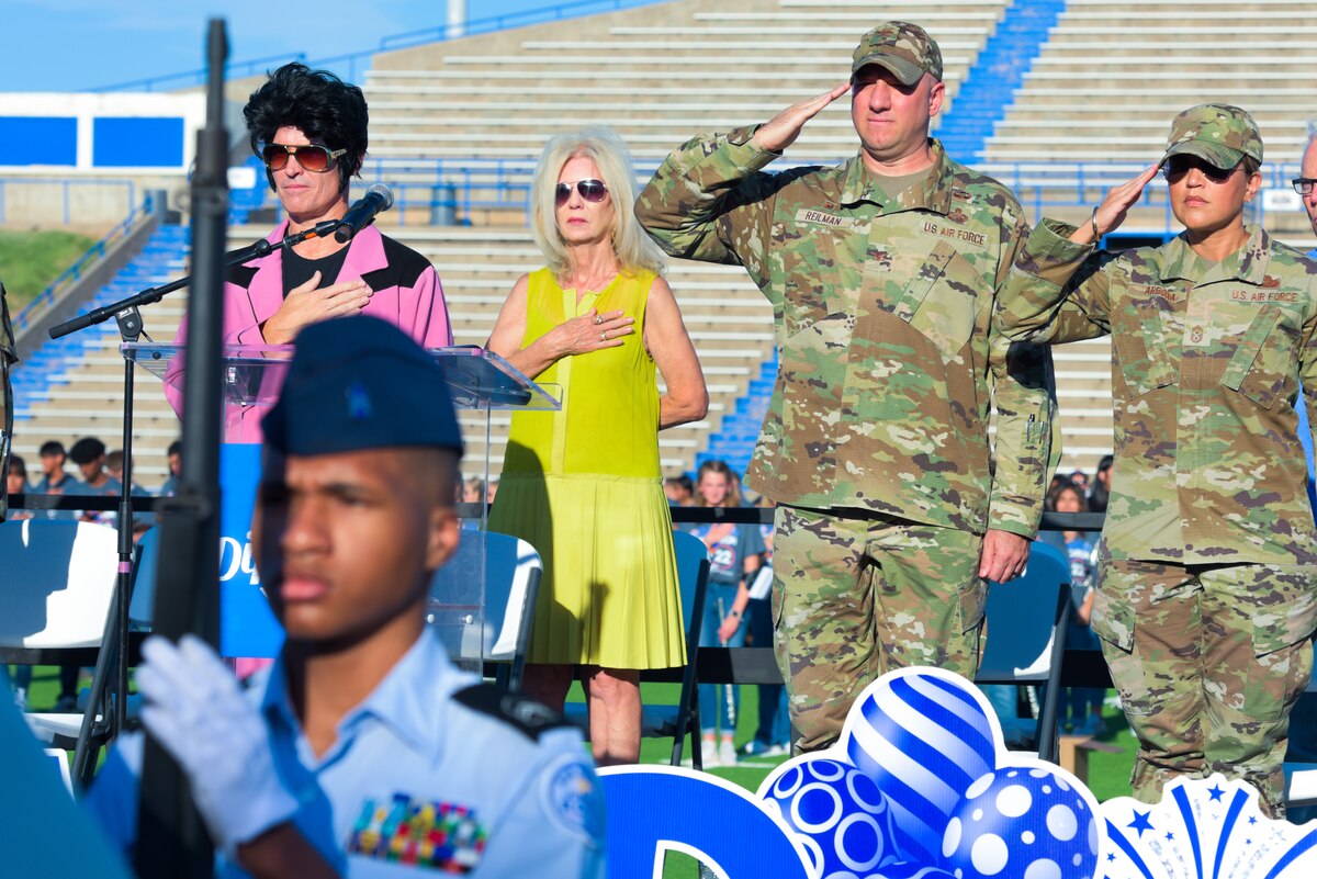 U.S. Air Force Col. Matthew Reilman, 17th Training Wing commander; Chief Master Sgt. Rebecca Arbona, 17th TRW command chief; and City of San Angelo mayor, Brenda Gunter, face the flag and render proper courtesies during the playing of the national anthem at the San Angelo Independent School District convocation, San Angelo Stadium, Texas, August 10, 2022. The convocation marks the beginning of the new school year for students attending school within SAISD. (U.S. Air Force photo by Senior Airman Michael Bowman)
