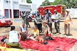 People with fake injuries evaluated on red sheet on the ground.