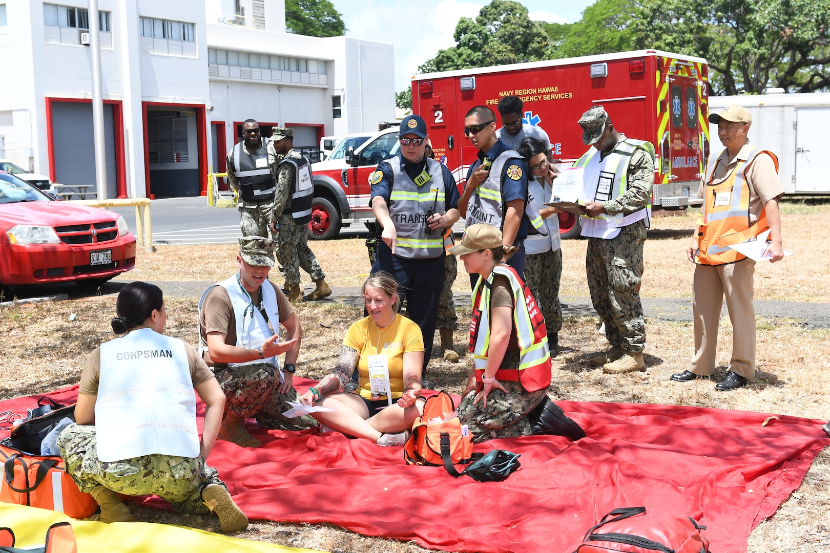 People with fake injuries evaluated on red sheet on the ground.