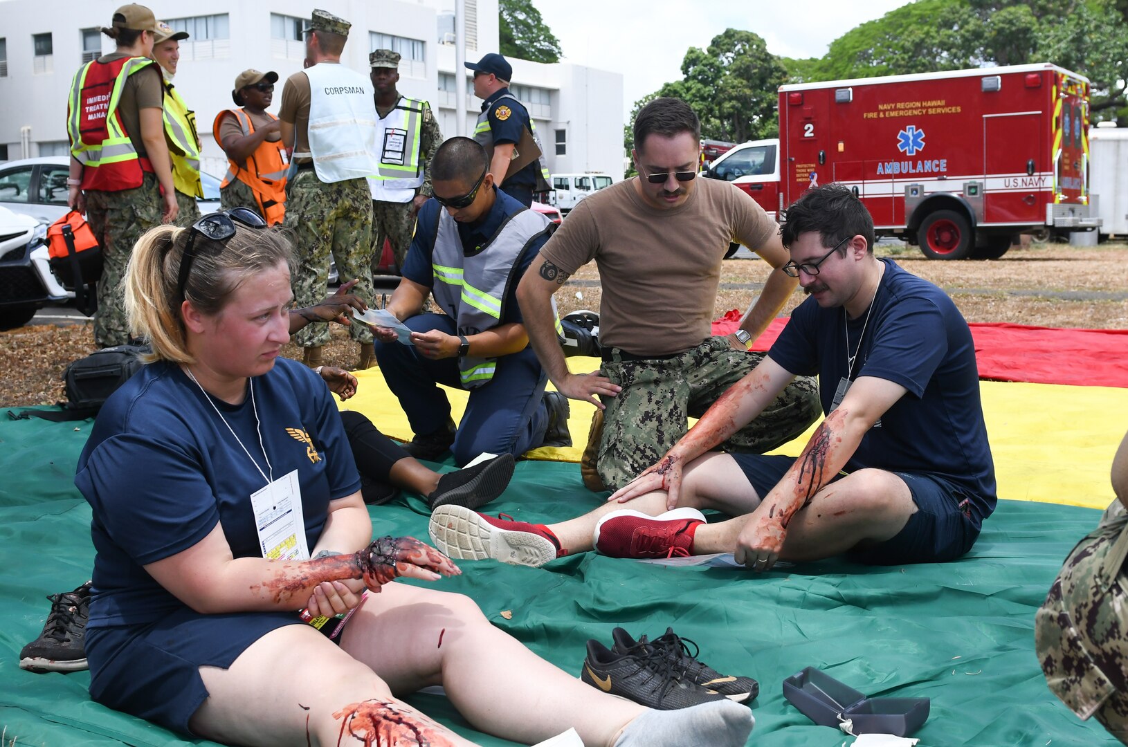 People with simulated injuries sitting on a sheet on the ground.