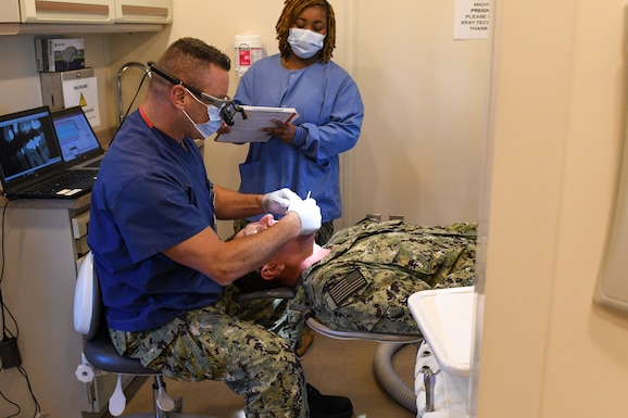 Dentist performs dental exam on patient.