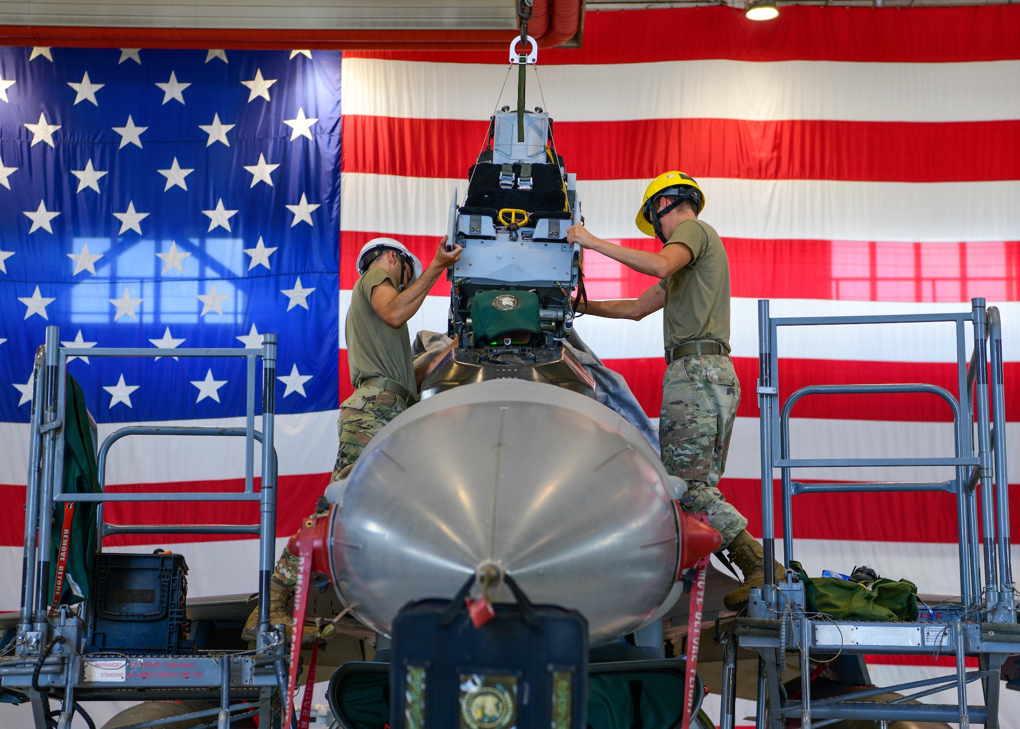 Airman 1st Class Jehaun Thomas, left, and Senior Airman Andres Espinoza, 31st Maintenance Squadron Egress journeymen, put a seat into an F-16 Fighting Falcon at Aviano Air Base, Italy, Aug. 11, 2022. Egress specialists perform scheduled and unscheduled maintenance on egress systems including the seat, cockpit, canopy and transparency. (U.S. Air Force photo by Senior Airman Brooke Moeder)