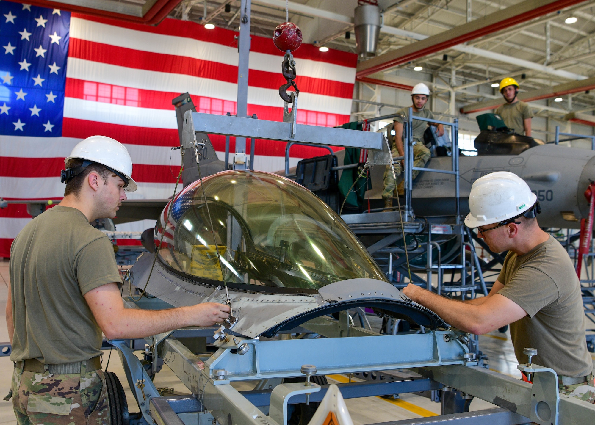 Airman 1st Class Nelson Wallace, 31st Maintenance Squadron Egress journeyman, and Tech. Sgt. Matthew Boe, 31st MXS Egress NCOIC, prepare to put a canopy on an F-16 Fighting Falcon canopy at Aviano Air Base, Italy, Aug. 11, 2022. Each seat and canopy have controlled explosives that safely launch a pilot when they eject. (U.S. Air Force photo by Senior Airman Brooke Moeder)