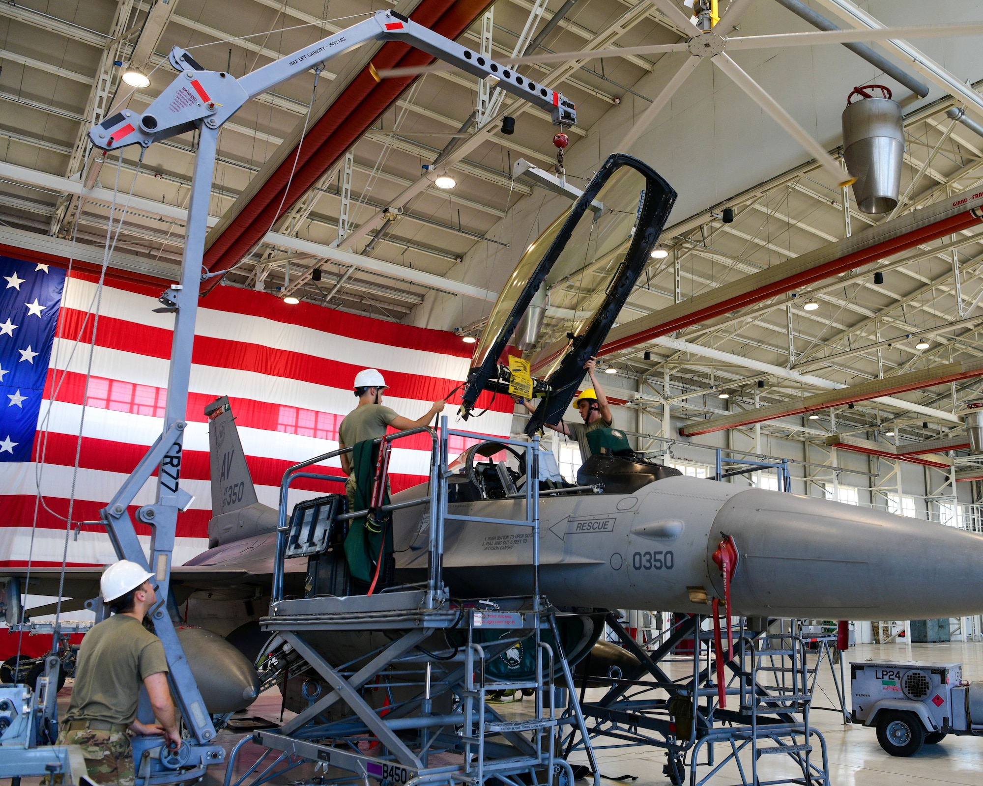 U.S. Air Force Airmen assigned to the 31st Maintenance Squadron Egress shop place a canopy onto an F-16 Fighting Falcon at Aviano Air Base, Italy, Aug. 11, 2022. Aviano was chosen as one of six bases across multiple major commands that have different environmental factors to test a new Luna transparency for the F-16 canopy. (U.S. Air Force photo by Senior Airman Brooke Moeder)