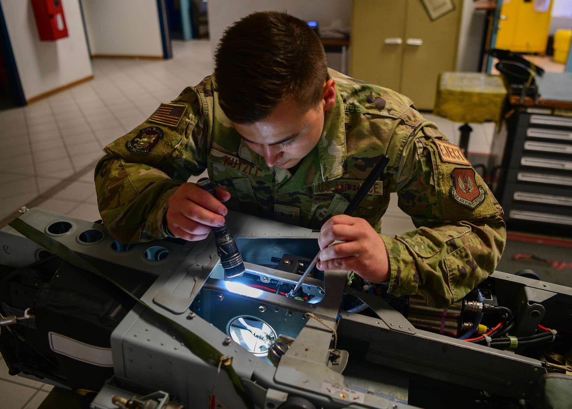 Senior Airman Reece Kutzli, 31st Maintenance Squadron Egress journeyman, inspects different components on an F-16 Fighting Falcon seat at Aviano Air Base, Italy, Aug. 10, 2022. The F-16 Fighting Falcon has an ejection mechanism that launches the canopy and propels the pilot out of the aircraft. (U.S. Air Force photo by Senior Airman Brooke Moeder)