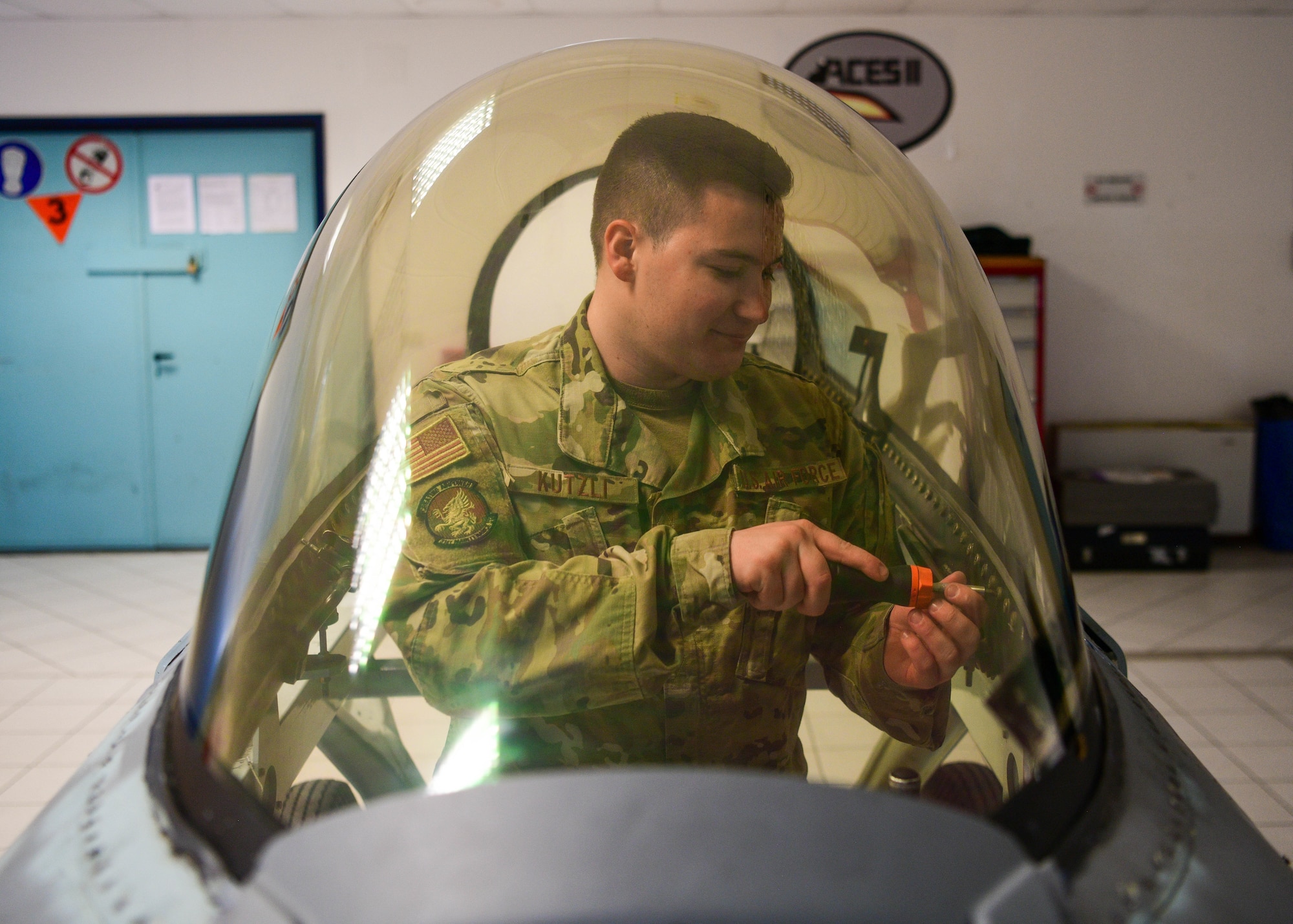 Senior Airman Reece Kutzli, 31st Maintenance Squadron Egress journeyman, screws bolts into an F-16 Fighting Falcon canopy at Aviano Air Base, Italy, Aug. 10, 2022. Aviano was chosen as one of six bases across multiple major commands that have different environmental factors to test a new Luna transparency for the F-16 canopy. (U.S. Air Force photo by Senior Airman Brooke Moeder)