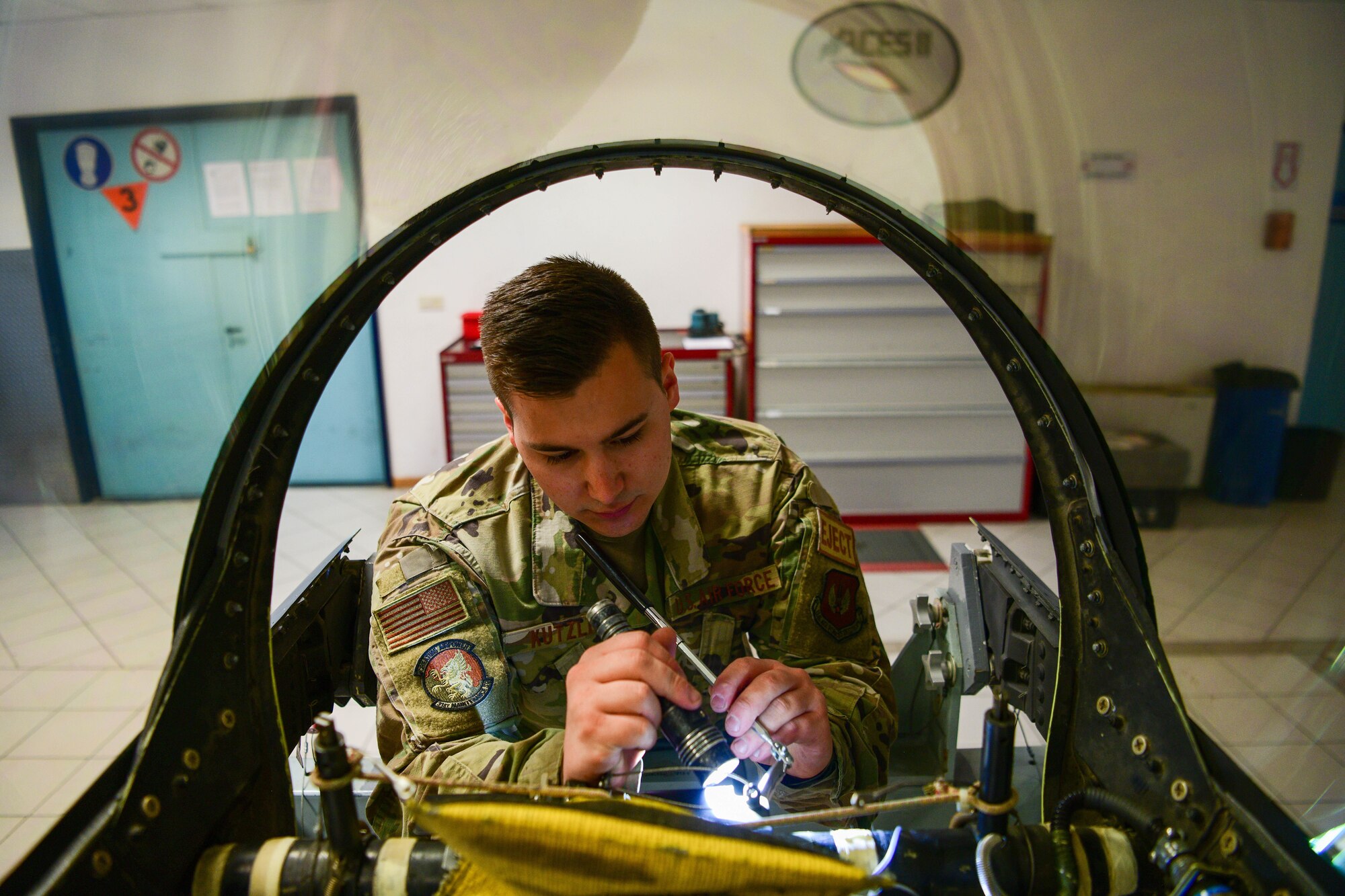 Senior Airman Reece Kutzli, 31st Maintenance Squadron Egress journeyman, screws bolts into an F-16 Fighting Falcon canopy at Aviano Air Base, Italy, Aug. 10, 2022. Six bases across multiple major commands that have different environmental factors were chosen to test a new Luna transparency for the F-16 canopy, which is supposed to reduce the amount of water that sticks to the glass at certain angles. (U.S. Air Force photo by Senior Airman Brooke Moeder)