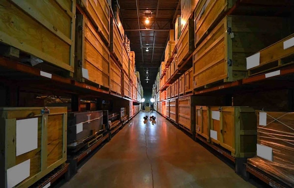 A view of one of the warehouse aisles where stacks and stacks of artifacts belonging to the National Cryptologic Museum stretch into the darkness beyond.