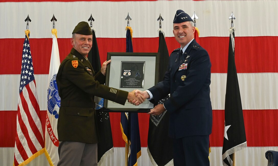 U.S. Space Force Lt. Gen. Stephen Whiting, commander of Space Operations Command, presents a plaque with the Army Satellite Operations Brigade and Space Force Delta 8 patches to U.S. Army Lt. Gen. Daniel Karbler, commander of U.S. Army Space and Missile Defense Command, during a ceremony at Peterson Space Force Base, Aug. 15, 2022. The ceremony marked the official transition of the satellite communications mission from the brigade to the delta, consolidating all military SATCOM functions under one service for the first time. (U.S. Space Force photo by Airman 1st Class Kaitlin Castillo)