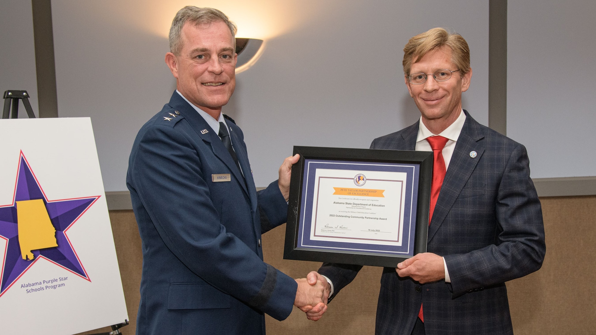 Maj. Gen. Jeff Hinrichs, mobilization assistant to the commander and president of Air University, presents the 2022 Pete Taylor Partnership of Excellence for Outstanding Community Partnership award to Dr. Eric Mackey, Alabama state superintendent of education, during the Alabama State Department of Education board meeting in downtown Montgomery, Ala., Aug. 11, 2022. The award was also presented to the school district superintendents in the River Region. Air University and Maxwell Air Force Base’s public education coalition, the River Region Partnership for Educational Excellence, received the award, which is the Military Child Education Coalition’s highest award. (U.S. Air Force photo by Trey Ward)