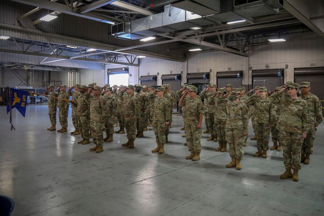 U.S. Air Force Reservists in uniform stand in formation and salute their new commander.