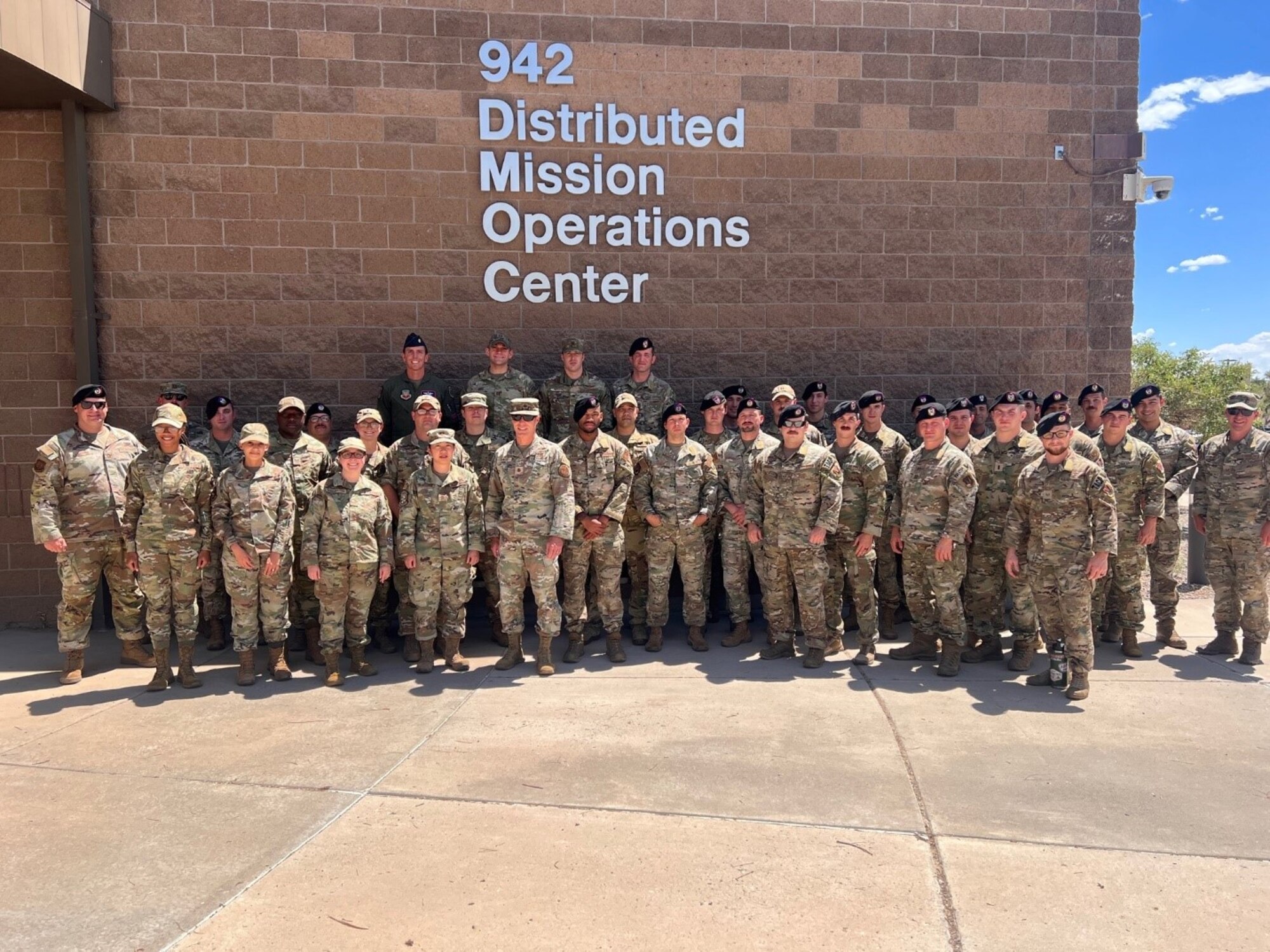 photo of a large group of military members in front of building that says 942 Distributed Mission Operations center
