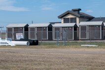 Temporary dog kennels occupy the front of the 341st Security Forces Squadron military working dog compound during indoor kennel construction Aug. 4, 2022, at Malmstrom Air Force Base, Mont. Renovations to the compound include upgrading the indoor kennels with a plumbing system, installing outdoor lights for night-training and replacing current vinyl obstacle course structures with permanent concrete replacements. (U.S. Air Force photo by Airman 1st Class Elijah Van Zandt)