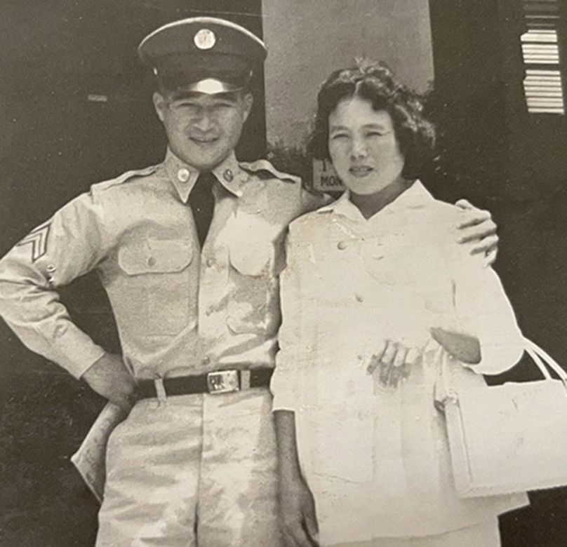 A man in uniform stands with his arm around a woman.
