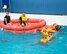 Two instructors in a large life raft watch as five people swim to the raft to get inside, practicing what they would do if their aircraft downed over a body of water.