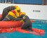 Three people in a life raft help lift another person inside.
