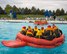 Two large circle life rafts filled with 20 people each float in a pool.