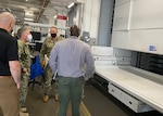 Four men stand in a warehouse