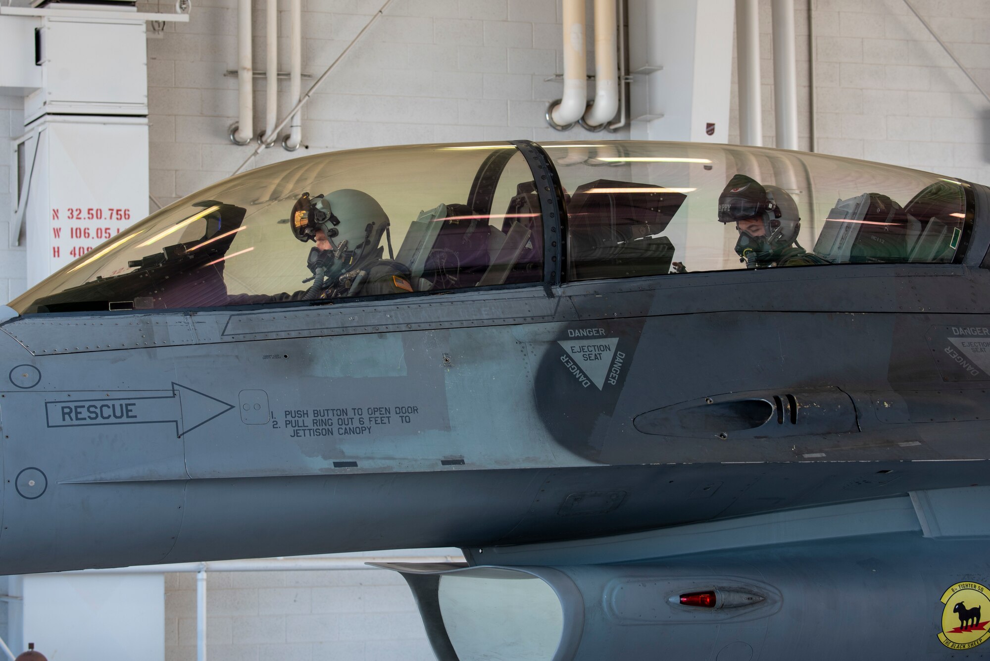 Colonel Justin Spears and Major Michael McCann sit inside the cockpit of an F-16 Viper.