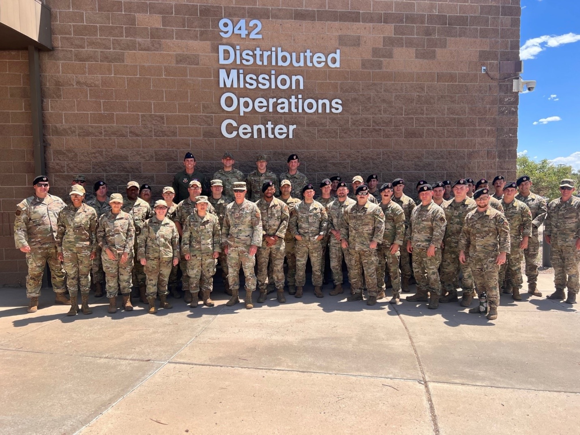 photo of a large group of military members in front of building that says 942 Distributed Mission Operations center