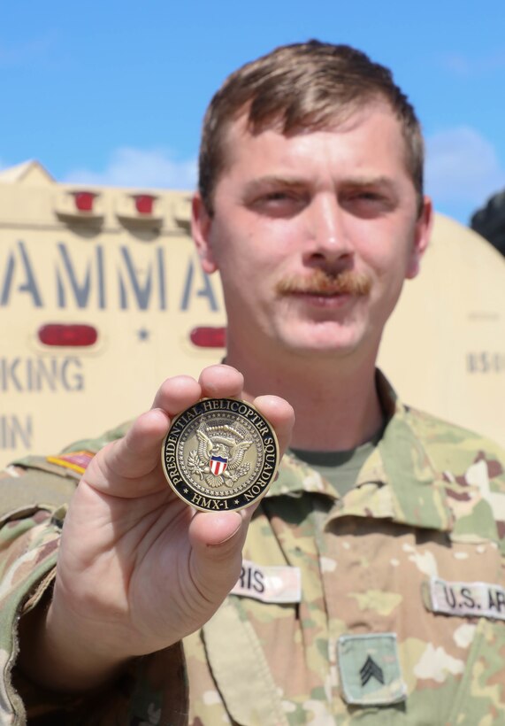 Army Sgt. William ‘Cecil’ Harris, a fuel Supply specialist with Detachment 1, Carlie Co. 2-238th Aviation- ‘Wildcat DUSTOFF’ poses for photo in front of his HEMMTT fuel truck with the Marine One coin he was given for helping refuel the presidents helicopter while he was in Kentucky