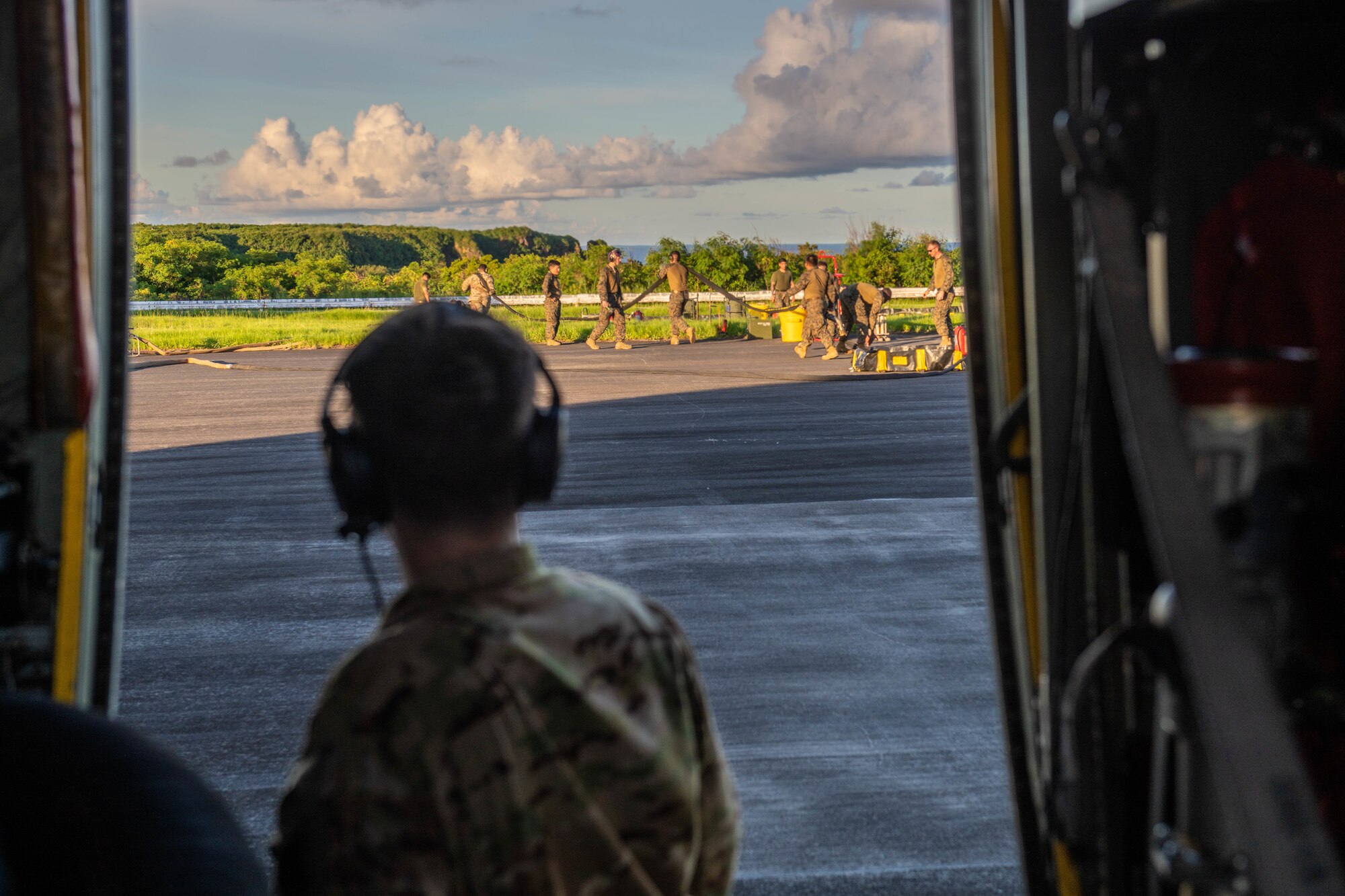 Airmen assist Marines with a forward aerial refueling point by guiding a fuel hose to an empty fuel bladder