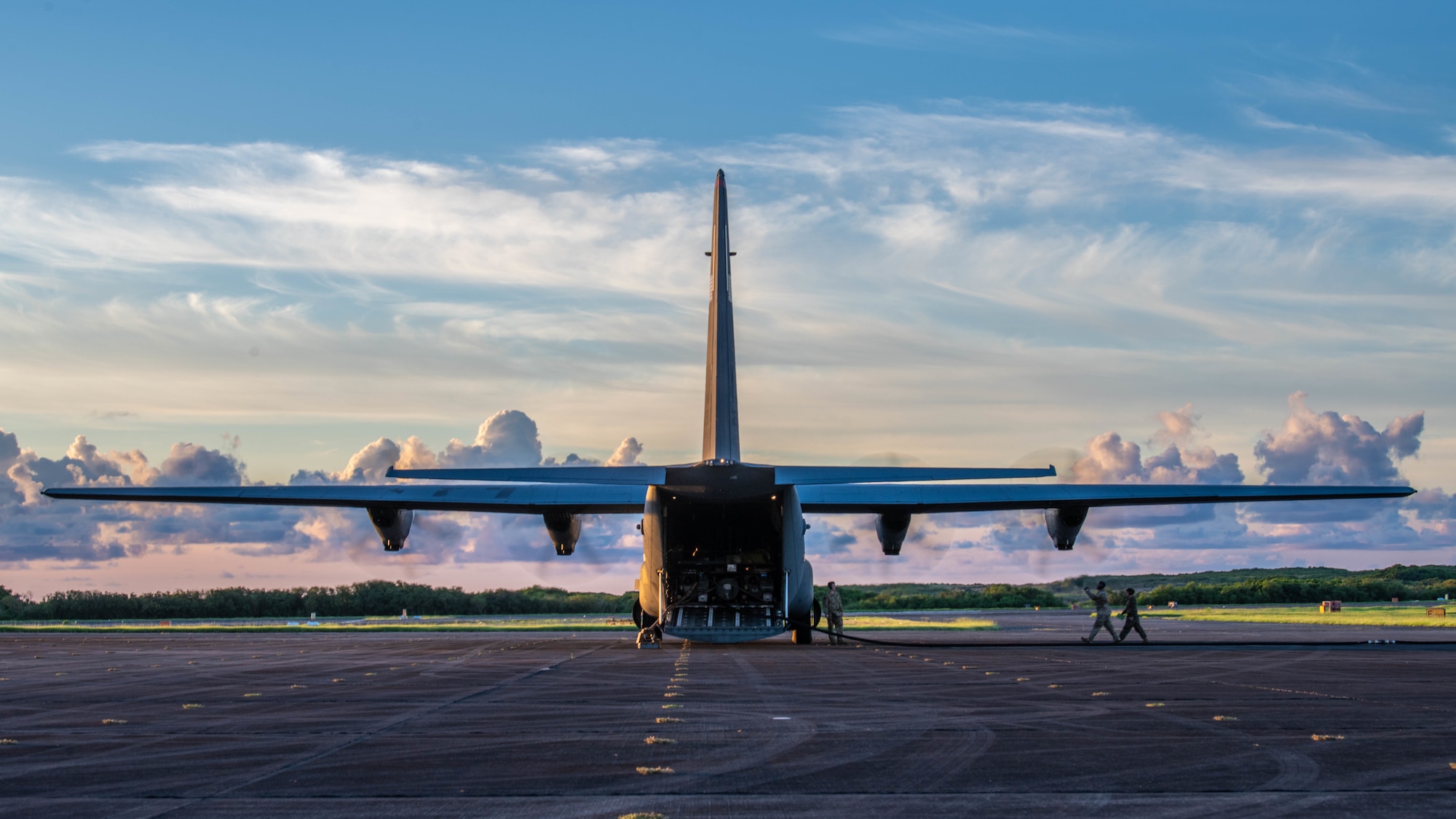 Airmen walk toward a C-130J Super Hercules during a fuel off-load