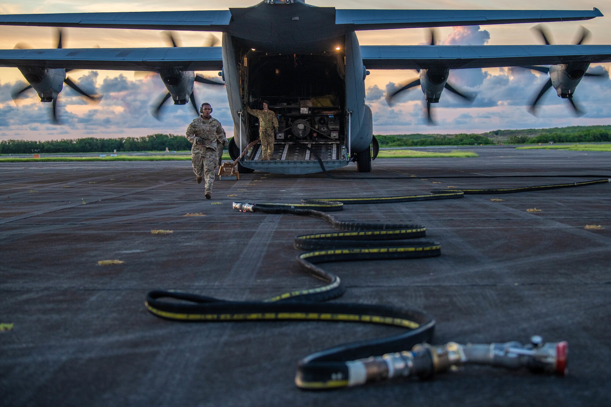 An Airman runs towards a fuel hose outside of a C-130J Super Hercules