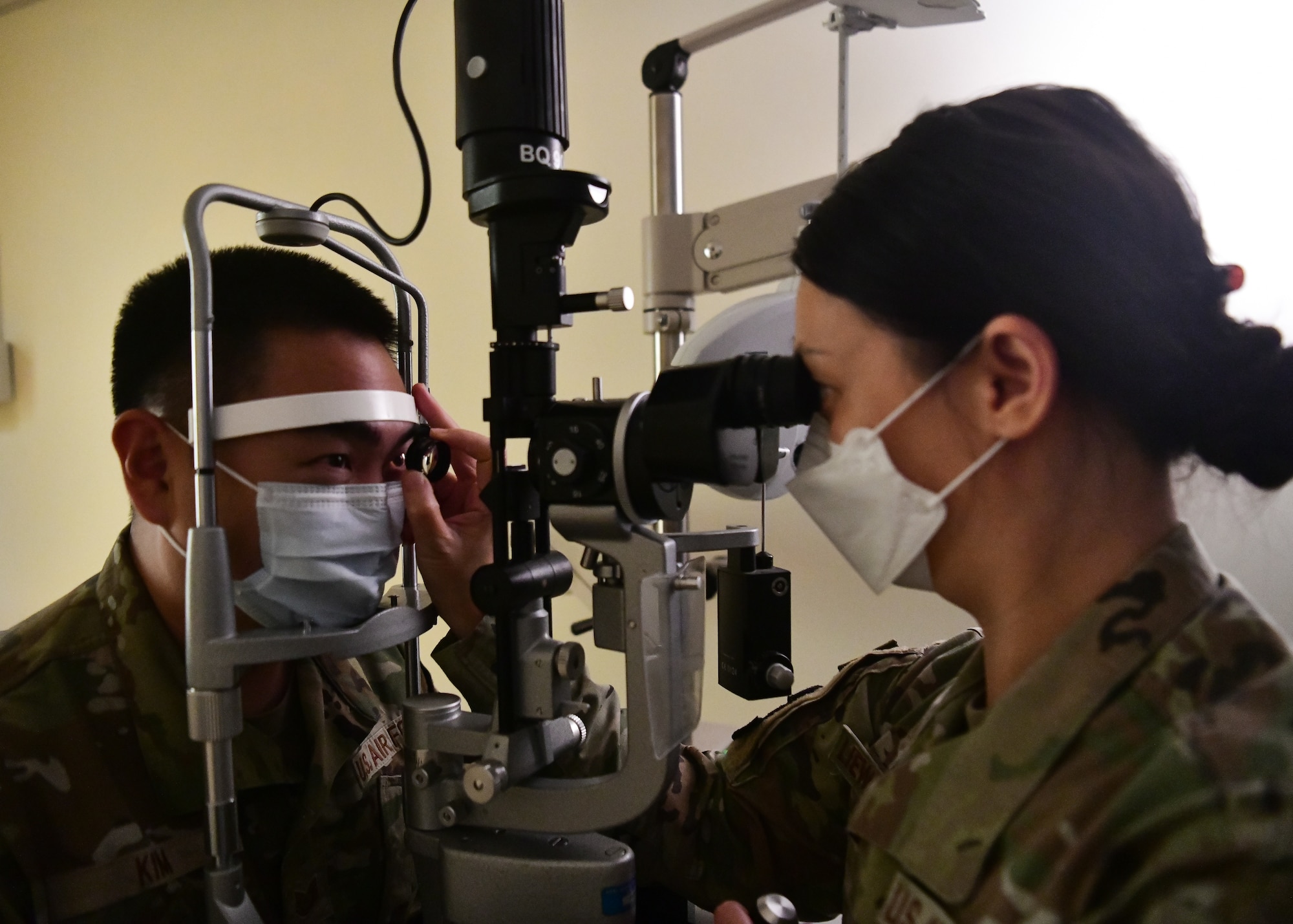 A military member conducts an eye exam on another military member.