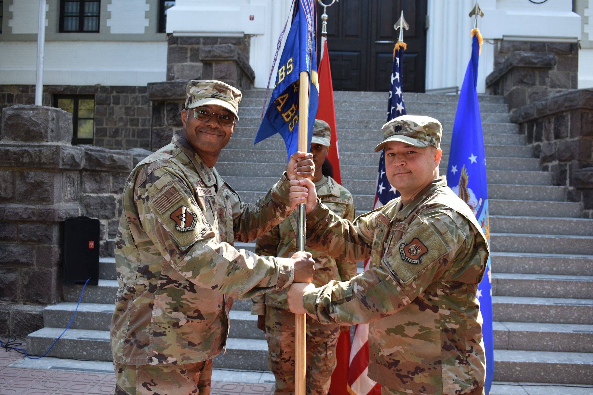 Col. Christopher Robinson, 39th Mission Support Group commander (left) accepts the guidon from Lt. Col. Todd Rotramel, outgoing 425th Air Base Squadron commander, as he relinquishes command of the 425th ABS during a change of command ceremony Aug. 15, 2022, at Izmir, Türkiye. Robinson officiated the ceremony. (U.S. Air Force photo by Tanju Varlıklı)