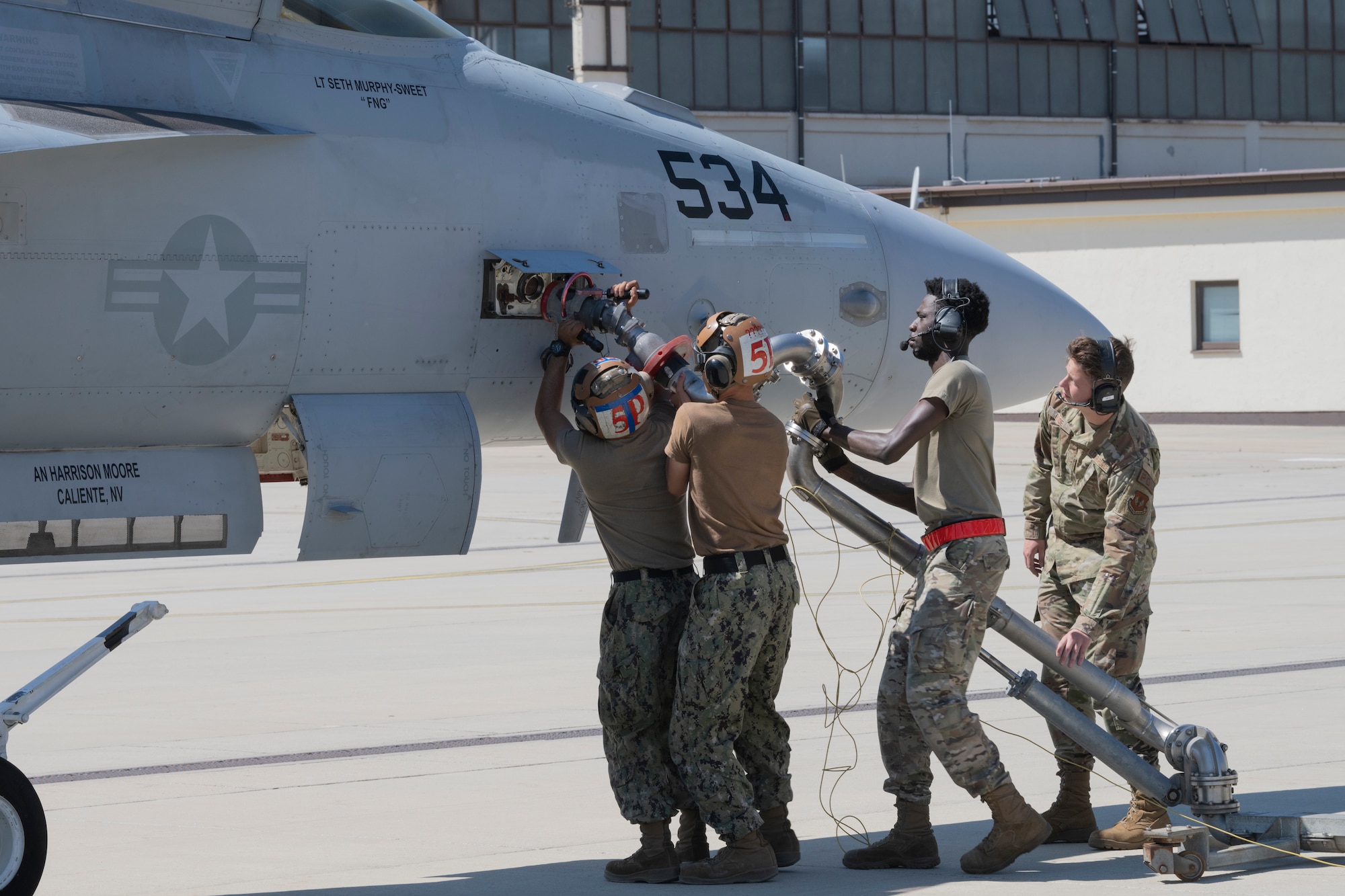 Service members participate in a joint hot-refueling on a electronic attack aircraft.