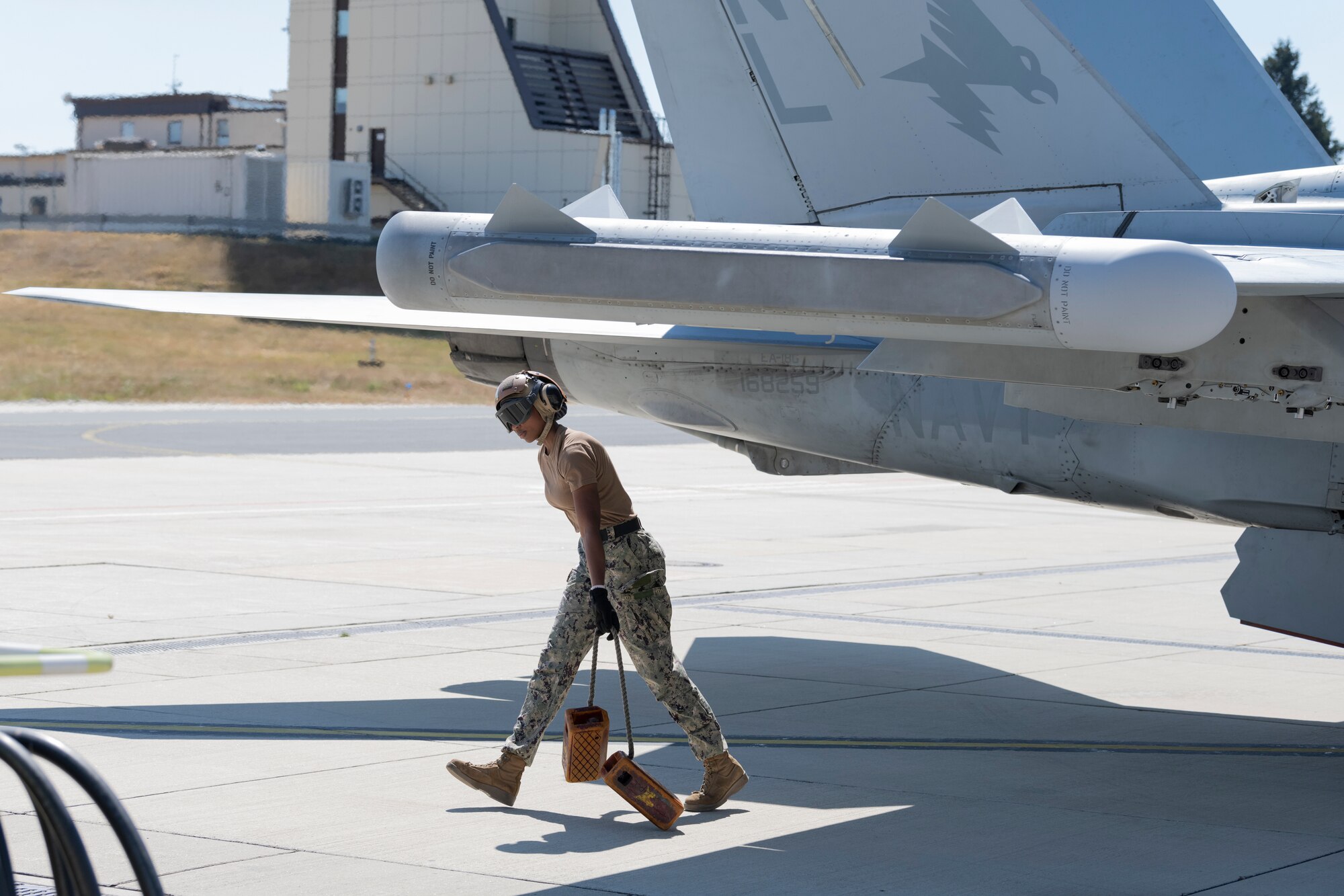 Service members participate in a joint hot-refueling on a electronic attack aircraft.