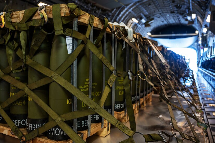 Pallets of ammunition are strapped down in the cargo hold of an aircraft.