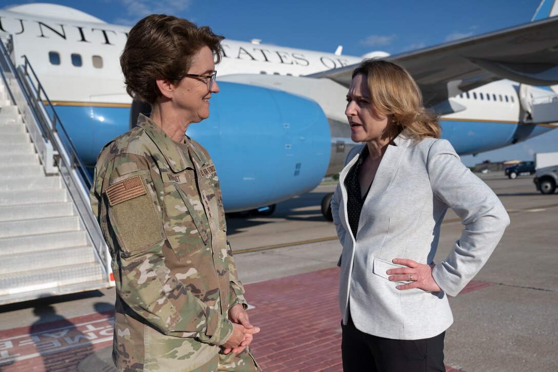 Two women talk near an aircraft.