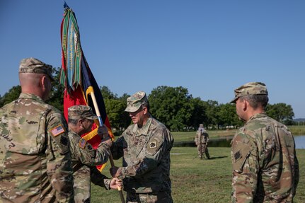 Brig. Gen. Thomas Mancino, adjutant general for Oklahoma, passes the unit colors to Col. Andrew Ballenger, incoming commander of the 45th Infantry Brigade Combat Team, at a change of command ceremony, Camp Gruber Training Center, Oklahoma, Aug. 14, 2022. Ballenger has served in the Army National Guard for over 30 years and has received many awards, to include a Legion of Merit and two Bronze Star Medals. (Oklahoma Army National Guard photo by Spc. Danielle Rayon)