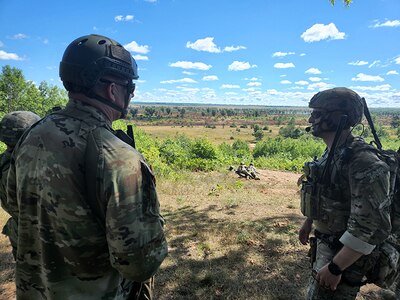 Sgt. 1st Class Ron Hesson, Army National Group Operations Group Wolf Fire Support Team Senior Observer, Coach/ Trainer, discusses a Fires Plan with Air National Guard Senior Airman Jake Decker, 113th Air Support Operations Squadron, during Northern Strike 2022 on August 9, 2022 at Camp Grayling, Michigan.