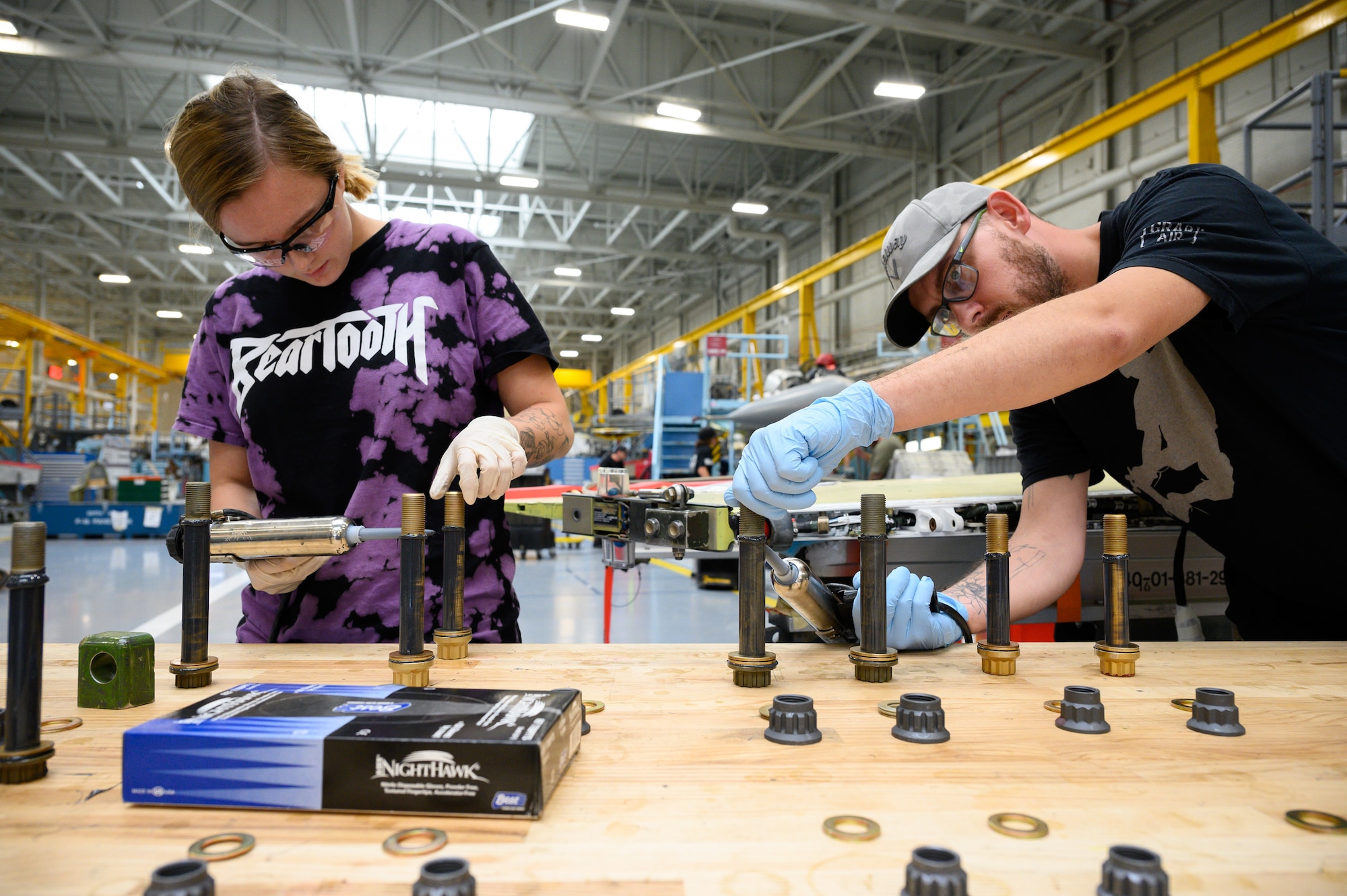 Left, Cheyanne Cummings and Cody Lupcho, 573rd Aircraft Maintenance Squadron, prepare hardware for a wing installation on an F-16 Fighting Falcon undergoing a Service Life Extension Program work package at Hill Air Force Base, Utah, Aug. 4, 2022.