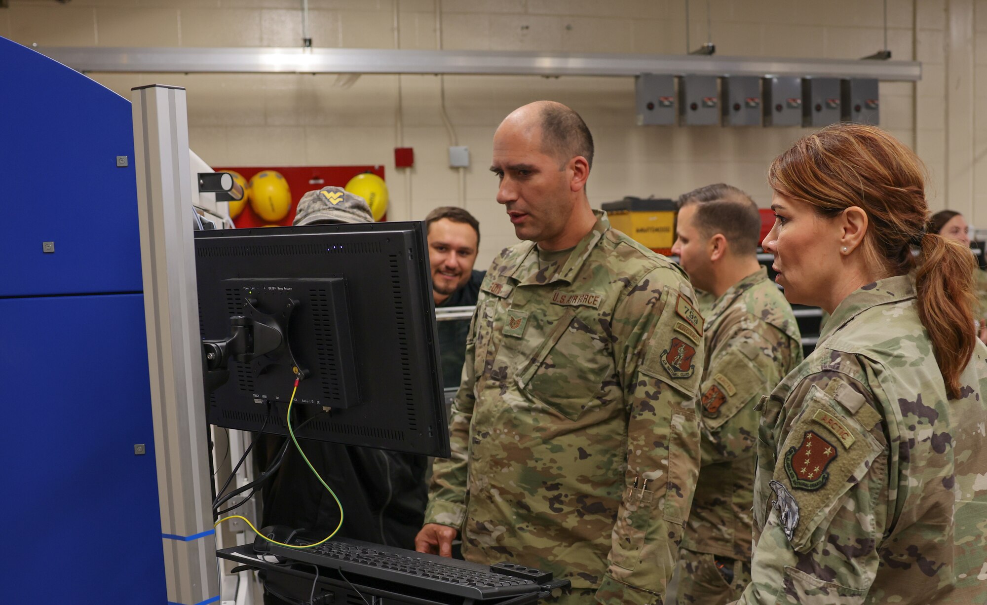 Airmen look at 3D printer
