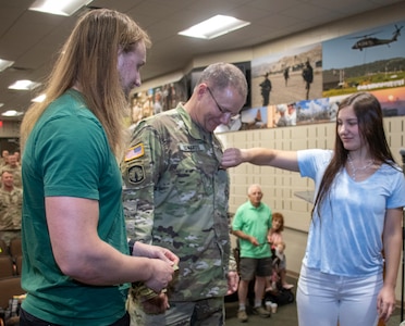 Newly promoted Col. Randy Edwards, of Decatur, Illinois, hands son, Gable Edwards, new rank as the promotion order is read during the ceremony Aug. 18 at the Illinois Military Academy, Camp Lincoln, in Springfield, Illinois.