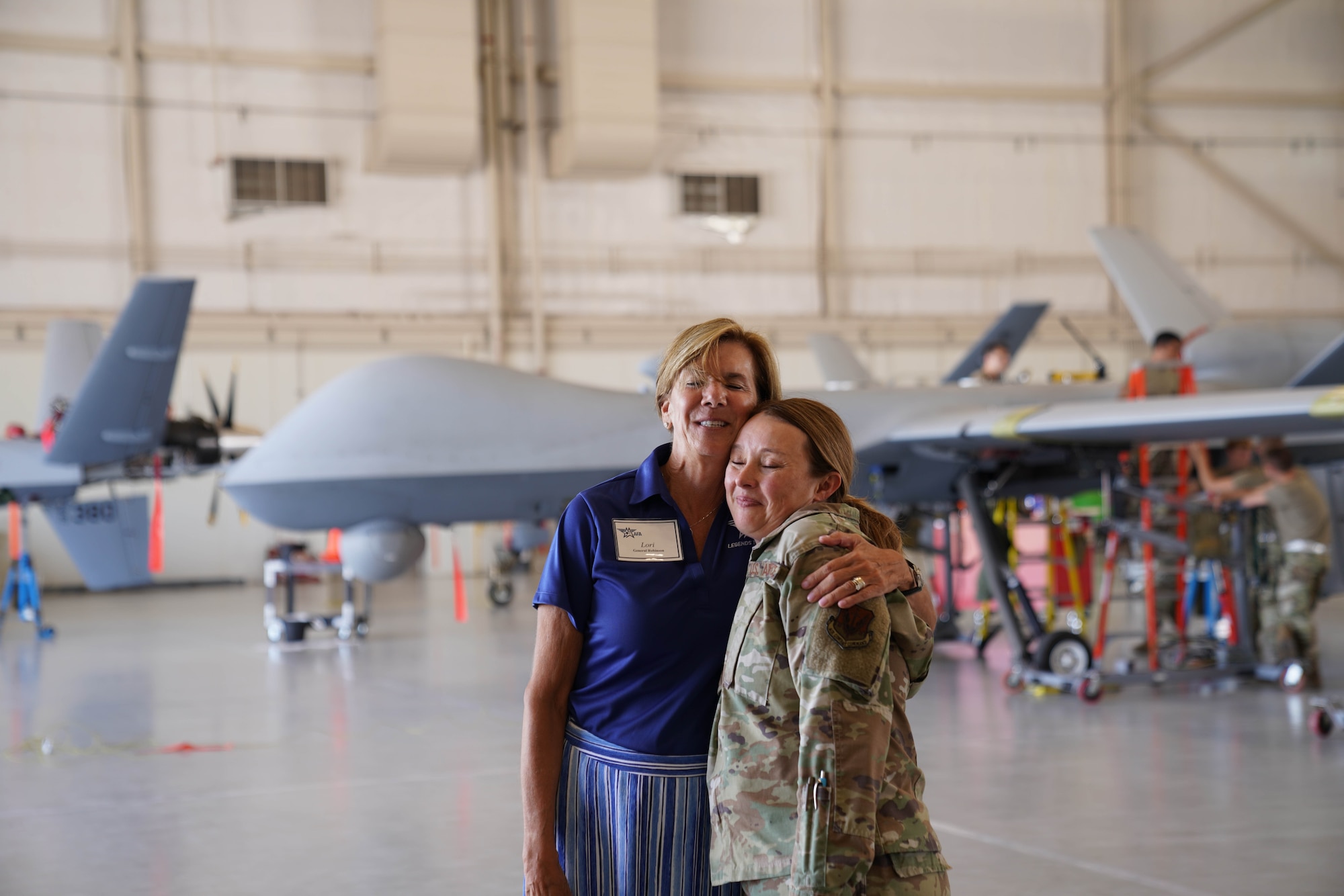 A woman embraces a female military member in uniform.
