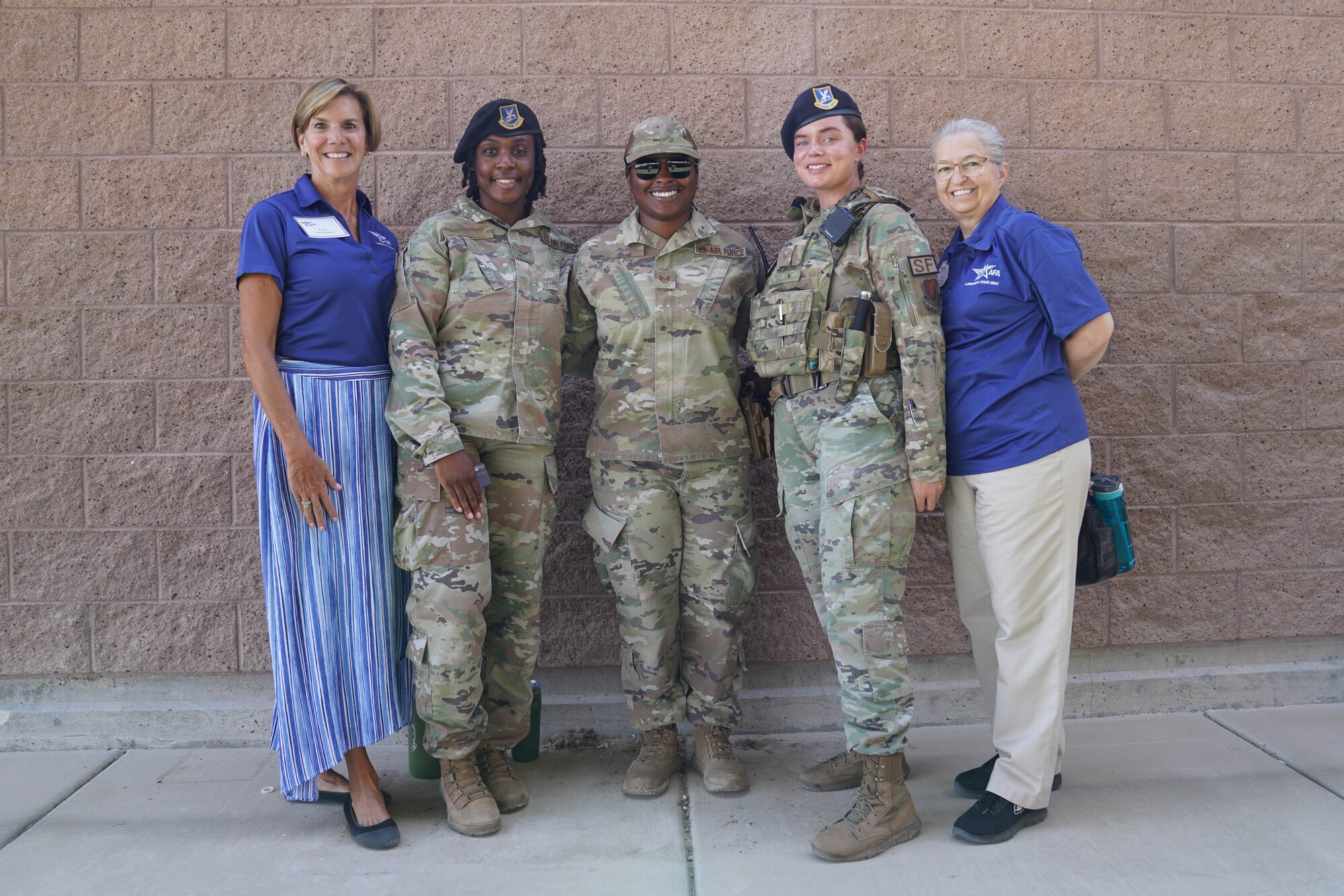 Three military members in uniform pose with two retirees smiling.