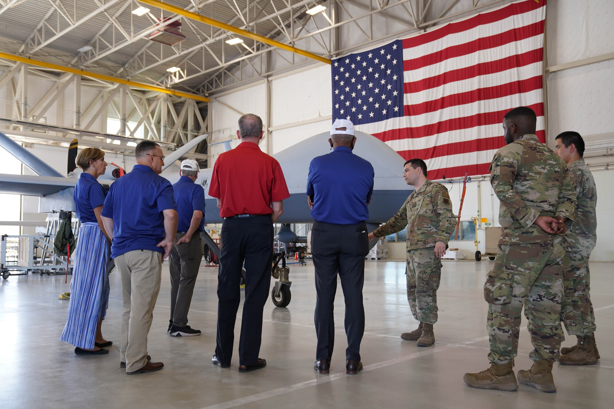 A military member in uniform speaks with a group of active duty and retired military in front of an aircraft.