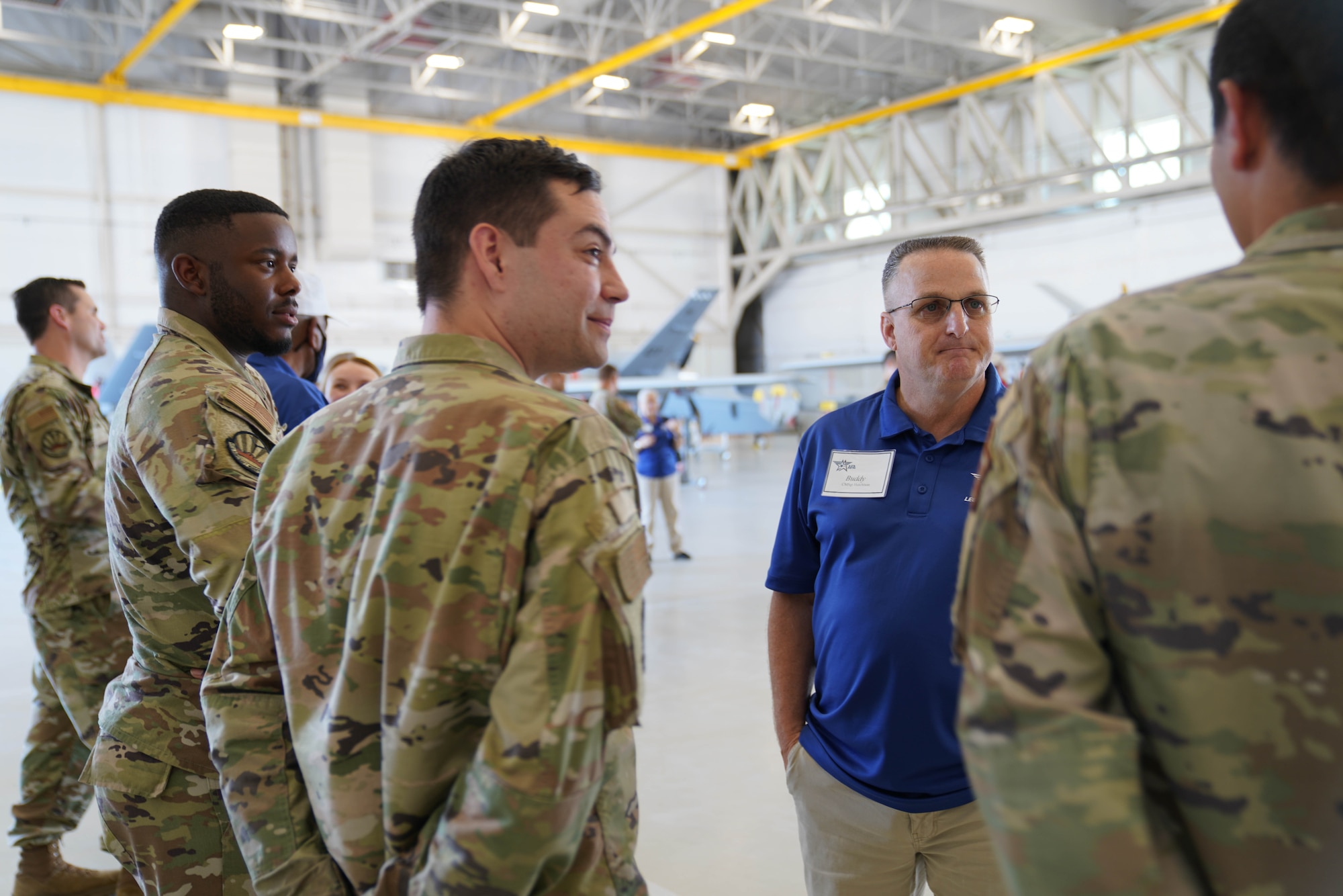 Retired chief master sergeant stands talking to three military members in uniform.