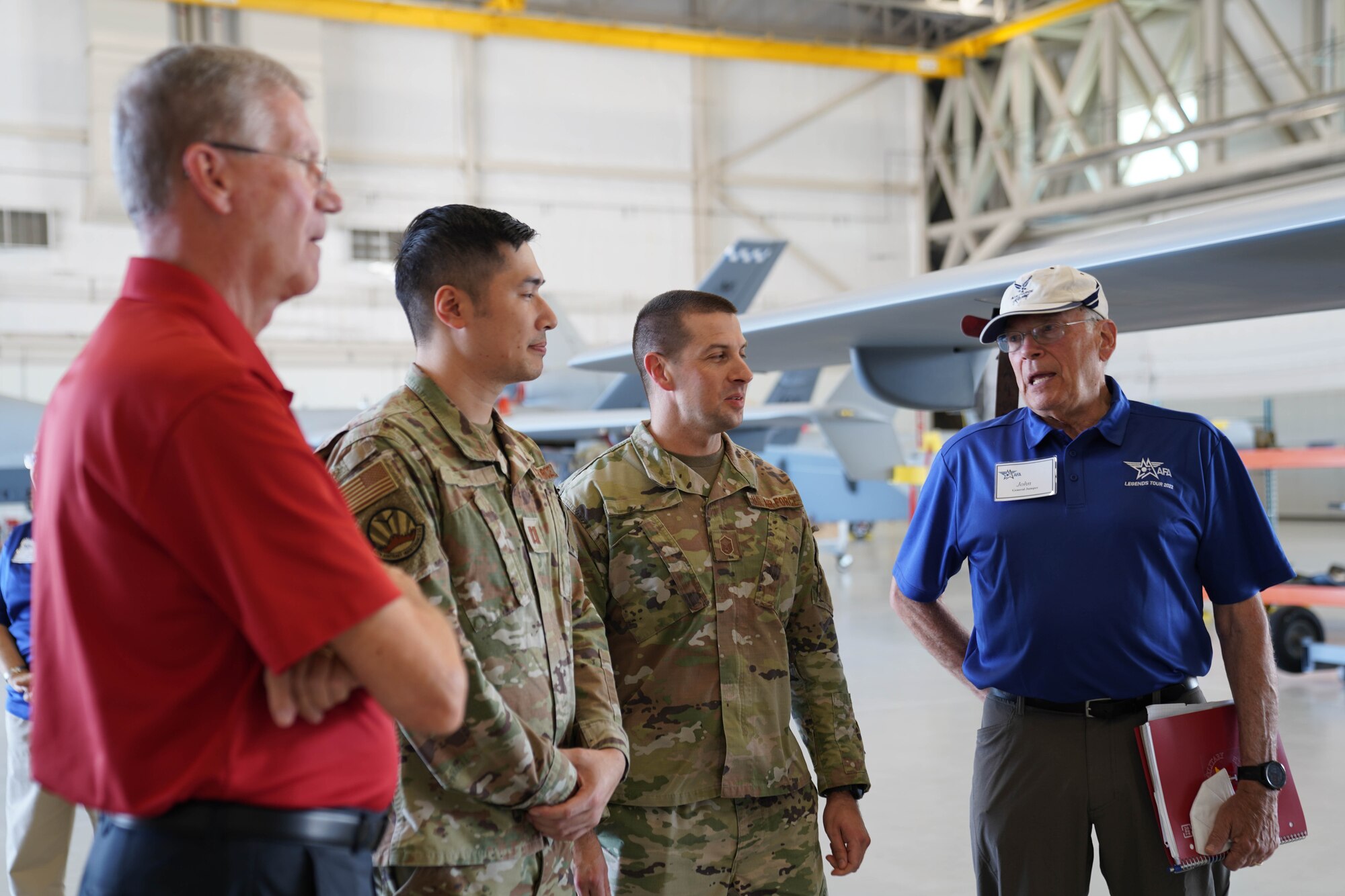 Retired Air Force general speaking with three active duty military members in uniform.