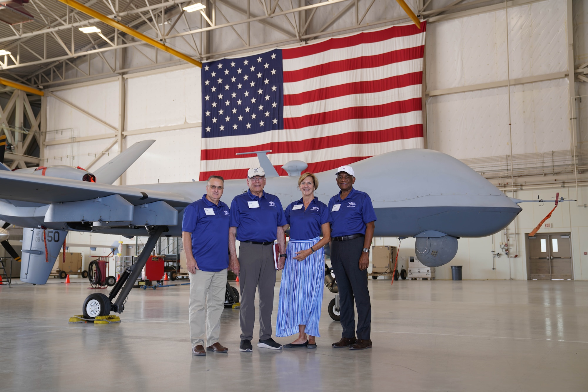 Group of four retired service members pose in front of MQ-9 aircraft.