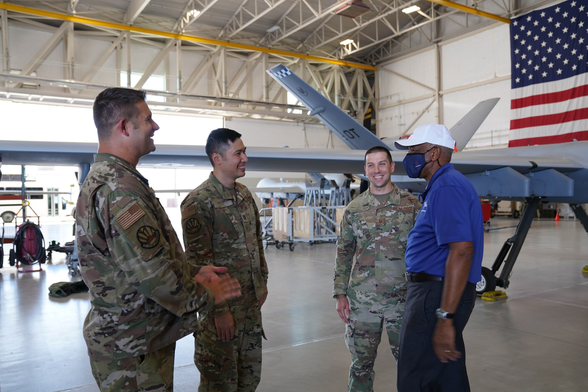 Retired general wearing face mask converses with three men in uniform.