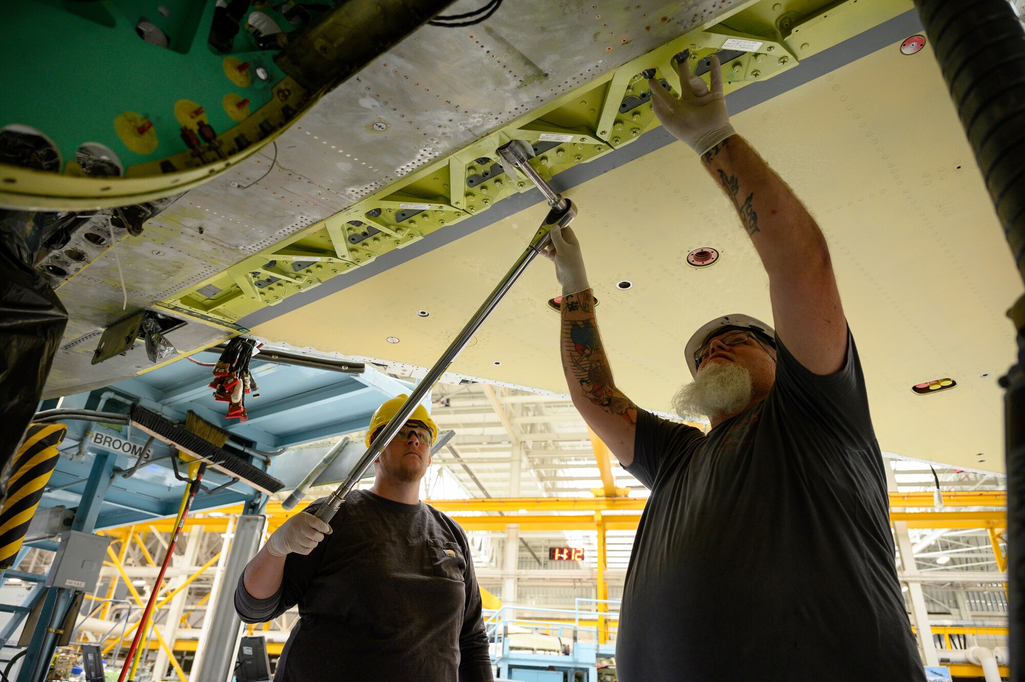 Right, Mike Minchey and Evan Mallory, 573rd Aircraft Maintenance Squadron, install a wing onto an F-16 Fighting Falcon undergoing a Service Life Extension Program work package at Hill Air Force Base, Utah, Aug. 4, 2022.