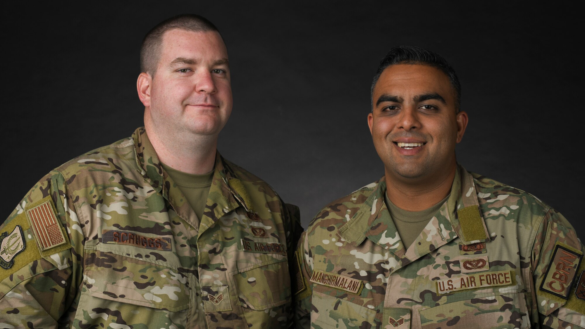 Two uniformed Airmen stand side-by-side and smile for a photo